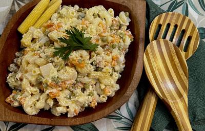 Foto da Receita de Macarronese. Observa-se um recipiente de madeira escuro com a macarronese. Ao lado direito, duas colheres grandes de servir. Foto da Receita de Macarronese. Observa-se um recipiente de madeira escuro com a macarronese. Ao lado direito, duas colheres grandes de servir.