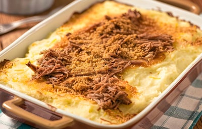 Refratário com fricassê dourado e gratinado por cima, com queijo derretido e batata palha, mostrando o recheio cremoso de carne desfiada no interior. Refratário com fricassê dourado e gratinado por cima, com queijo derretido e batata palha, mostrando o recheio cremoso de carne desfiada no interior.