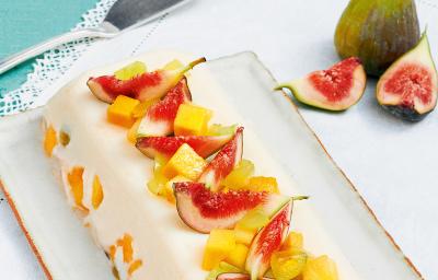 Fotografia em tons de branco e azul claro de uma bancada vista de cima, contém um pano branco, uma travessa branca retangular que contém a sobremesa de gelatina com diversas frutas por cima para decorar. Fotografia em tons de branco e azul claro de uma bancada vista de cima, contém um pano branco, uma travessa branca retangular que contém a sobremesa de gelatina com diversas frutas por cima para decorar.
