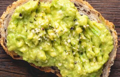 Sobre uma tabua de madeira, uma torrada com um creme verde e sementes de gergelim Sobre uma tabua de madeira, uma torrada com um creme verde e sementes de gergelim