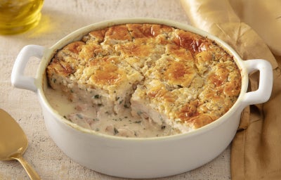 Caçarola cremosa assada com frango e molho branco, gratinada com superfície dourada, servida em refratário branco.