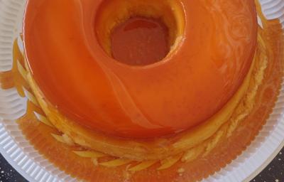 Fotografia de um pudim inteiro com caramelo dentro de um recipiente fundo branco de plástico. Fotografia de um pudim inteiro com caramelo dentro de um recipiente fundo branco de plástico.