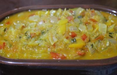 Fotografia de uma moqueca de ovo e mamão verde dentro de um recipiente escuro. Fotografia de uma moqueca de ovo e mamão verde dentro de um recipiente escuro.