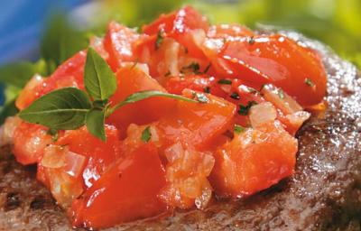Fotografia em tons de vermelho e verde, com hambúrguer ao centro com tomate picado e folhas de manjericão sobre folhas verdes e fundo azul. Fotografia em tons de vermelho e verde, com hambúrguer ao centro com tomate picado e folhas de manjericão sobre folhas verdes e fundo azul.
