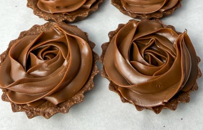 Fotografia em tons claros de algumas tarteletes de brigadeiro com massa de chocolate ao centro