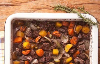 em uma mesa de madeira contém um recipiente com o picadinho com cenoura, mandioquinha e salsão.