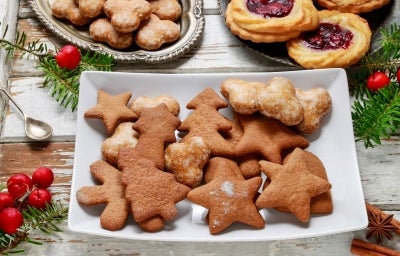 Em cima de uma mesa, prato com biscoitos em formato de estrelas e árvores de Natal. Em cima de uma mesa, prato com biscoitos em formato de estrelas e árvores de Natal.