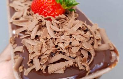 Fotografia de um bolo em forma retangular de chocolate com creme branco e brigadeiro. Por cima do bolo tem raspas de chocolate e morango. Fotografia de um bolo em forma retangular de chocolate com creme branco e brigadeiro. Por cima do bolo tem raspas de chocolate e morango.