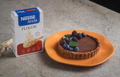 Foto da receita de Torta de Maçã com Chocolate e Nestlé Aveia Flocos, decorada com mirtilos, amoras e hortelã, servida em um prato laranja, sobre uma bancada de pedra onde está uma caixa de Nestlé Aveia Flocos e um ramo de trigo seco Foto da receita de Torta de Maçã com Chocolate e Nestlé Aveia Flocos, decorada com mirtilos, amoras e hortelã, servida em um prato laranja, sobre uma bancada de pedra onde está uma caixa de Nestlé Aveia Flocos e um ramo de trigo seco