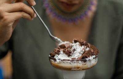 Fotografia de uma pessoa segurando uma colher de sopa e comendo uma sobremesa de camadas de massa e MOÇA Leite Condensado Cremoso. O doce está em uma tacinha de vidro. Fotografia de uma pessoa segurando uma colher de sopa e comendo uma sobremesa de camadas de massa e MOÇA Leite Condensado Cremoso. O doce está em uma tacinha de vidro.