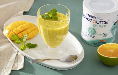 Fotografia em tons de amarelo com um pote de vidro ao centro. Dentro do pote existe uma receita de mousse de manga com laranja. Ao lado existe um pote de Novasource Proline Fotografia em tons de amarelo com um pote de vidro ao centro. Dentro do pote existe uma receita de mousse de manga com laranja. Ao lado existe um pote de Novasource Proline