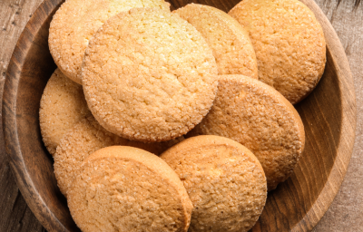 Imagem de pequenos biscoitinhos dispostos sobre um prato fundo de madeira, tons de dourado, amarelo e marrom. Imagem de pequenos biscoitinhos dispostos sobre um prato fundo de madeira, tons de dourado, amarelo e marrom.