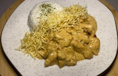 Fotografia de um prato de vidro branco com uam receita de estrogonofe de sobrecoxa com arroz e batata palha. Fotografia de um prato de vidro branco com uam receita de estrogonofe de sobrecoxa com arroz e batata palha.