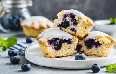 Fotografia em tons de branco com três bolinhos cupcakes ao centro. Os cupcakes são feitos com blueberries e cobertura de limão.