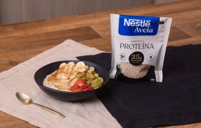 Receita de mingau com banana, morango, kiwi e mel, acompanhado de colher dourada e uma embalagem de nestlé aveia proteína Receita de mingau com banana, morango, kiwi e mel, acompanhado de colher dourada e uma embalagem de nestlé aveia proteína