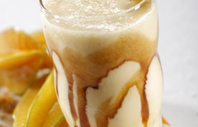 foto tirada de um copo transparente com bebida de carambola e sorvete com calda de caramelo. Ao fundo carambolas. foto tirada de um copo transparente com bebida de carambola e sorvete com calda de caramelo. Ao fundo carambolas.