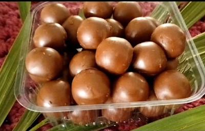 Fotografia de uma embalagem quadrada de plástico com vários bombons pequenos e redondos de açaí.