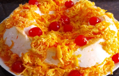 Foto em tons de amarelo da receita de pudim de clara de panetone com fio de ovos com cerejas por cima para decorar
