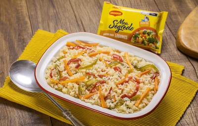 Fotografia mostra uma travessa com arroz com pimentões coloridos e uma colher servindo arroz.
