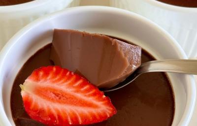 Fotografia em tons de branco com um vários potinhos brancos ao centro. Dentro dos potes existe uma receita de gelatina de chocolate finalizada com morango Fotografia em tons de branco com um vários potinhos brancos ao centro. Dentro dos potes existe uma receita de gelatina de chocolate finalizada com morango