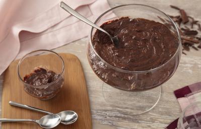 Foto da receita de Mousse Fácil de Chocolate. Observa-se um recipiente redondo com a mousse e, ao lado, um recipiente individual. Também tem duas colherinhas ao lado e raspas de chocolate como decoração. Foto da receita de Mousse Fácil de Chocolate. Observa-se um recipiente redondo com a mousse e, ao lado, um recipiente individual. Também tem duas colherinhas ao lado e raspas de chocolate como decoração.
