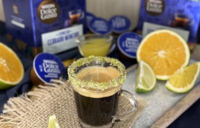 Foto da receita de Café Cítrico. Observa-se uma xícara pequena de vidro com a borda açucarada e o espresso dentro. Laranjas, limões e cápsulas de NESTLÉ DOLCE GUSTO Espresso Cerrado Mineiro decoram a foto.