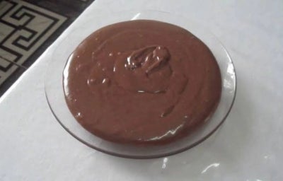 Brigadeiro de colher servido em prato de vidro transparente sobre superfície clara.