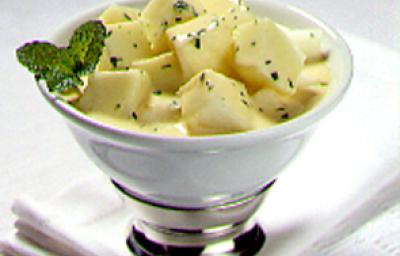 Fotografia em tons de amarelo em uma bancada de madeira, um pano branco, uma taça branca com o melão com creme de pêssego dentro. Fotografia em tons de amarelo em uma bancada de madeira, um pano branco, uma taça branca com o melão com creme de pêssego dentro.