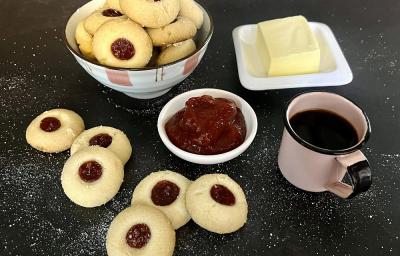 Foto da receita de mantecal com geleia em tons de vermelho servidos em um bowl de porcelana com adornos cor de rosa. À frente há alguns biscoitos mantecal soltos além de uma caneca de café e um recipiente com geleia e ao lado um recipiente com manteiga Foto da receita de mantecal com geleia em tons de vermelho servidos em um bowl de porcelana com adornos cor de rosa. À frente há alguns biscoitos mantecal soltos além de uma caneca de café e um recipiente com geleia e ao lado um recipiente com manteiga