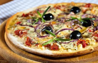Fotografia de uma pizza de massa fina com mozarela, gorgonzola, requeijão, tomate seco, orégano, cebola roxa e azeitonas pretas. A pizza está sobre um apoio de madeira. Fotografia de uma pizza de massa fina com mozarela, gorgonzola, requeijão, tomate seco, orégano, cebola roxa e azeitonas pretas. A pizza está sobre um apoio de madeira.