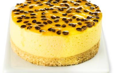 Fotografia em tons de amarelo em uma bancada e fundo branco, um recipiente branco retangular e a torta de maracujá com requeijão em cima dele.