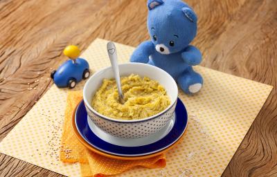 Fotografia em tons de laranja em uma bancada de madeira com um paninho amarelo de bolinha no centro e um potinho branco com bolinhas azuis com a sopinha de frango com abóbora. Ao lado, um ursinho de pelúcia azul e um carrinho azul de brinquedo. Fotografia em tons de laranja em uma bancada de madeira com um paninho amarelo de bolinha no centro e um potinho branco com bolinhas azuis com a sopinha de frango com abóbora. Ao lado, um ursinho de pelúcia azul e um carrinho azul de brinquedo.