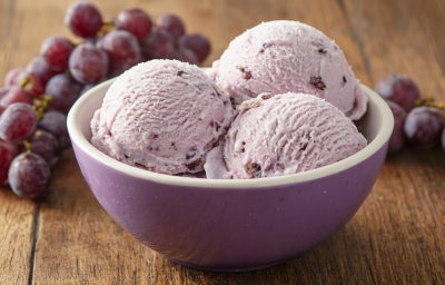 Fotografia de um sorvete de uva caseiro servido em um pote roxo