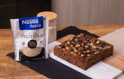 receita de bolo proteico molhadinho de banana e chocolate servida em uma porção grande sobre uma mesa de madeira decorada com um pote e uma embalagem de aveia proteína receita de bolo proteico molhadinho de banana e chocolate servida em uma porção grande sobre uma mesa de madeira decorada com um pote e uma embalagem de aveia proteína