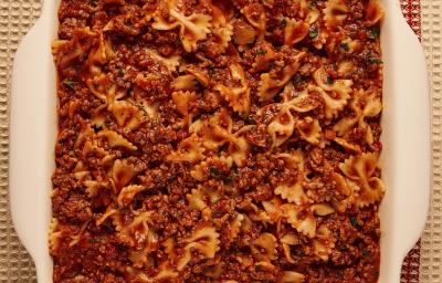 Foto bem aproximada de uma travessa branca com a receita de macarrão tipo gravatinha com molho bolonhesa