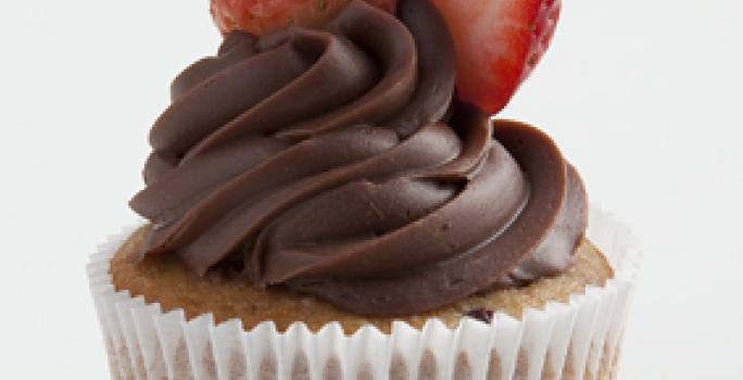 um bolinho com cobertura de chocolate por cima e frutas vermelhas para decorar