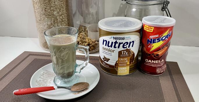 Imagem da receita de Cappuccino Proteico, sobre uma mesa, ao lado uma lata de Nutren Protein e Nescau Canela