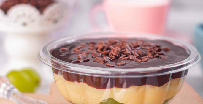 Fotografia mostra um pote transparente com camadas visíveis de uva verde, creme branco e chocolate com granulado.