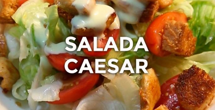 Foto da receita de Salada Caeser. Observa-se um prato com alface americana, tomates cereja, crouton, frango e molho