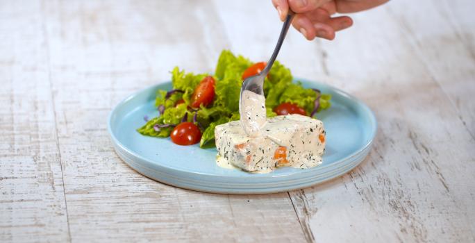Fotografia em tons de branco e azul de uma bancada branca, sobre ela um prato redondo azul com salão e salada.