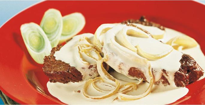 foto tirada de uma prato redondo e vermelho com dois bifes, creme por cima e cebolas