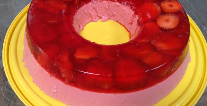 Foto em tons de vermelho da receita de super gelatina de morango servida sobre uma base circular amarela