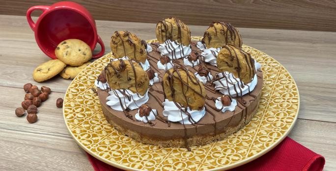 Fotografia mostra uma cheesecake de chocolate decorada com chantilly e cookies cobertos com chocolate.