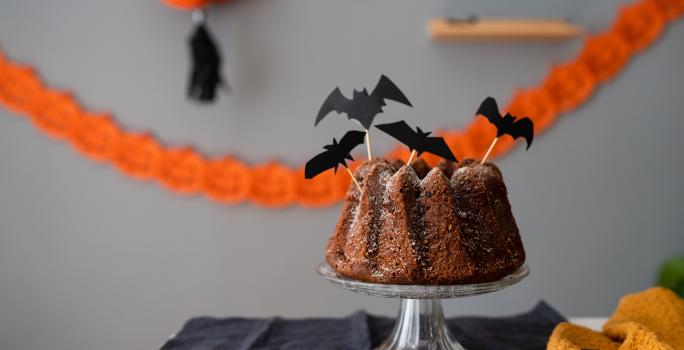 Fotografia de um bolo simples decorado com itens de dia das bruxas.