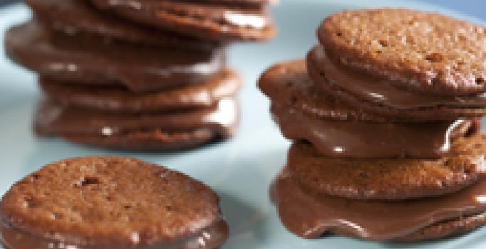 fotografia em tons de marrom, branco e azul tirada de uma bailarina branca com Whoopies Nescau por cima com recheio de brigadeiro