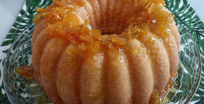 Foto da receita de Bolo Delícia de Tangerina. Observa-se um bolo bonito com furo no meio com geleia de tangerina por cima.