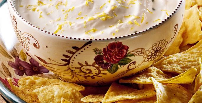 fotografia em tons de marrom e branco tirada de uma bancada vista de frente. Contém um recipiente com biscoitos, e um recipiente redondo branco por cima com um creme.