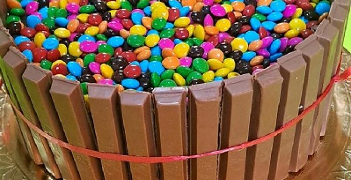 Foto em tons de marrom da receita de bolo de cerquinha decorado com confetes coloridos servida sobre uma base prateada