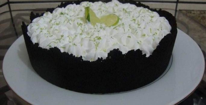 Foto da receita de Torta de Limão com Biscoito. Observa-se uma torta com base escura de chocolate em um prato branco.