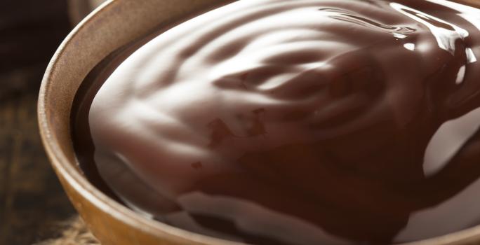 fotografia em tons de marrom tirada de um recipiente redondo com calda de chocolate dentro